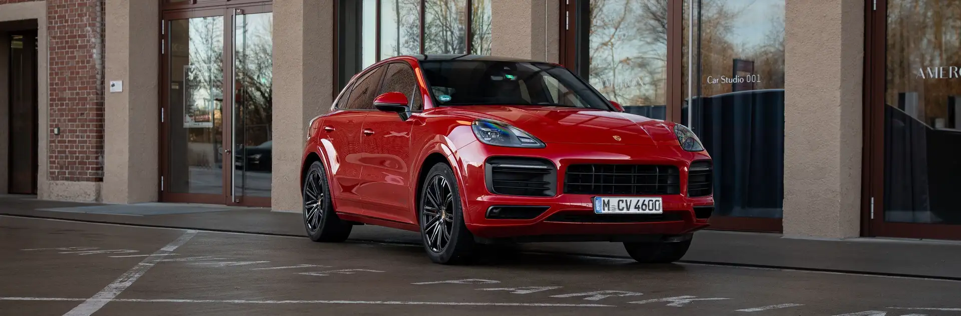 Unser roter Porsche Cayenne GTS in der Frontansicht vor einem Industriegebäude.